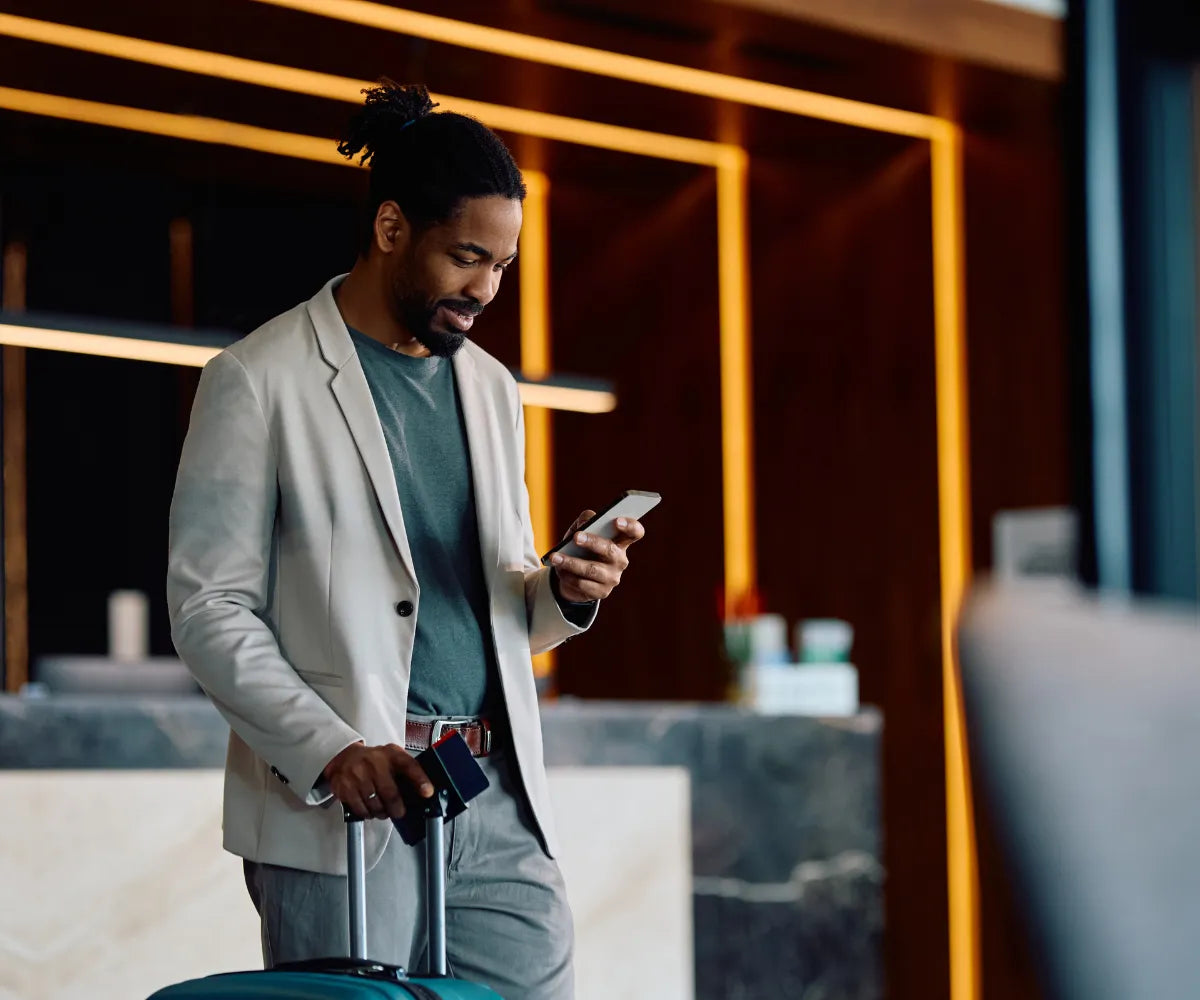 Man Looking at Phone After Checking In At Hotel