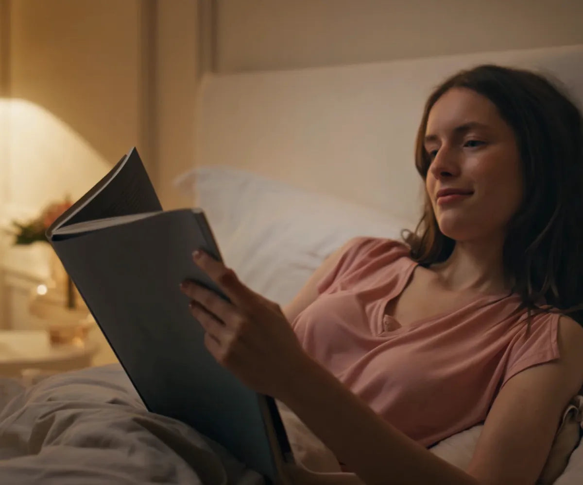 Woman In Bed Reading Book With Lights On