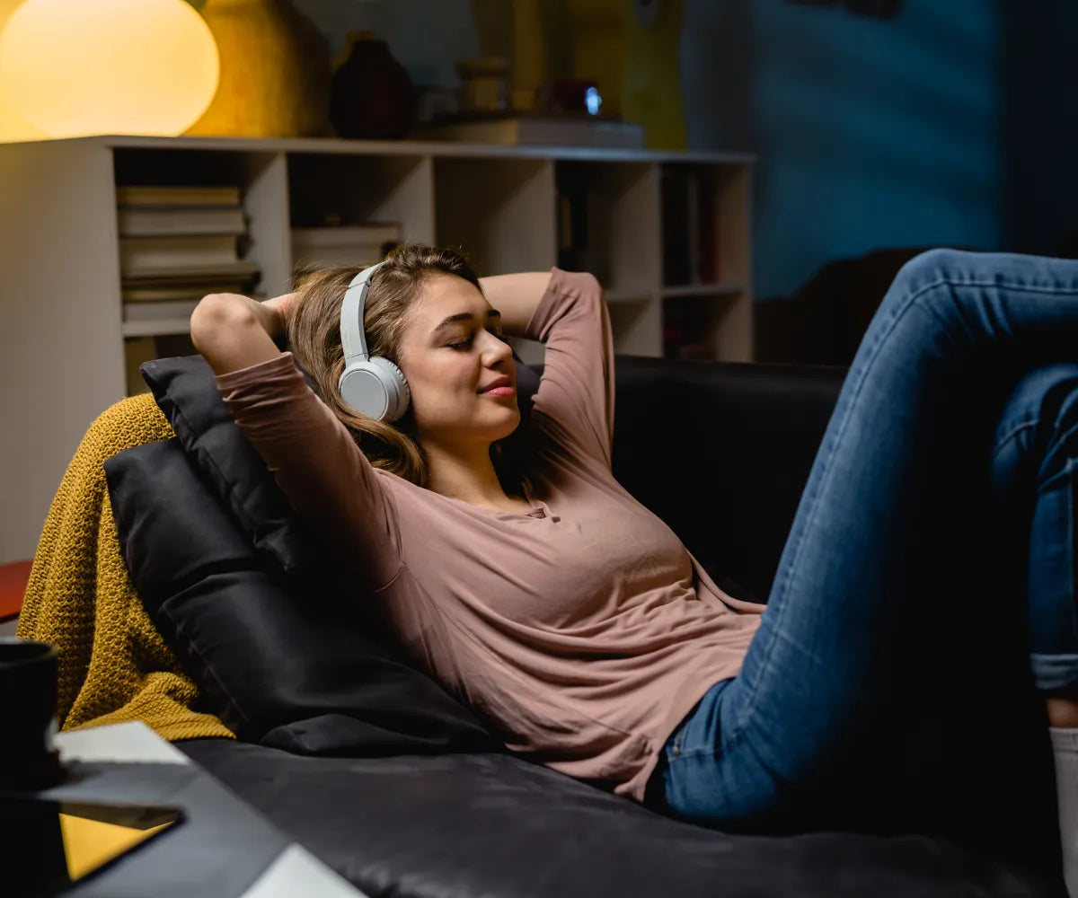 Woman Relaxing On Couch with Eyes Closed While Listening To Music
